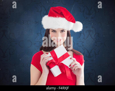 Zusammengesetztes Bild des festlichen Brünette Holding Geschenk Stockfoto