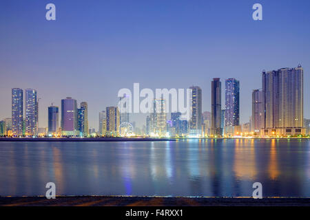 Nacht-Skyline-Blick auf moderne Apartment-Hochhäuser entlang der Corniche in Sharjah, Vereinigte Arabische Emirate Stockfoto