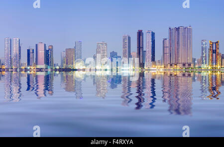 Nacht-Skyline-Blick auf moderne Apartment-Hochhäuser entlang der Corniche in Sharjah, Vereinigte Arabische Emirate Stockfoto