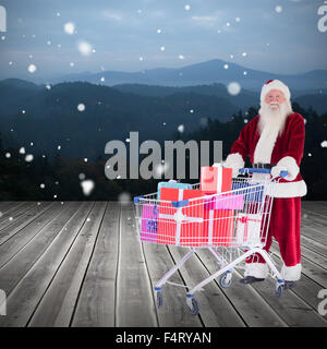 Zusammengesetztes Bild von Santa, die Geschenke aus dem Warenkorb zu liefern Stockfoto