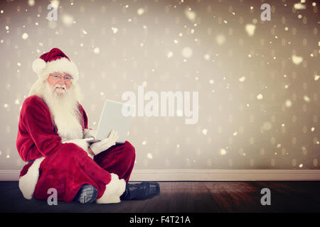 Zusammengesetztes Bild von Santa sitzt und einen laptop Stockfoto