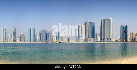 Tagsüber Skyline-Blick auf Strand und moderne Apartment-Hochhäuser entlang der Corniche in Sharjah, Vereinigte Arabische Emirate Stockfoto