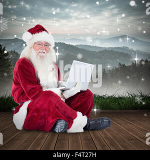 Zusammengesetztes Bild von Santa sitzt und einen laptop Stockfoto
