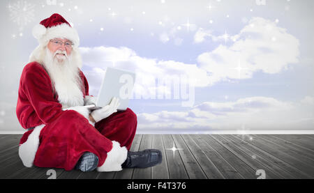 Zusammengesetztes Bild von Santa sitzt und einen laptop Stockfoto