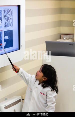 Japan, Nishinomiya, KidZania, Rollenspiele, Freizeitzentrum für Kinder. Kind, Mädchen Wissenschaftler, im weißen Mantel, Vortrag, der auf. Stockfoto