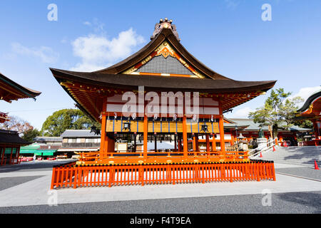 Japan, Koyto, Fushimi. Berühmte Inari Schrein. Zinnoberrot verzierten Shinto Bühne Gebäude in der Mitte des leeren Innenhof. Strahlender Sonnenschein. Blue Sky. Stockfoto