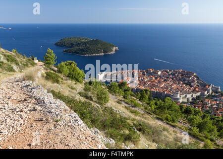 Blick auf einen steinigen Weg auf den Berg Srd, der ummauerten Altstadt und Insel Lokrum bei Dubrovnik, Kroatien von oben. Stockfoto