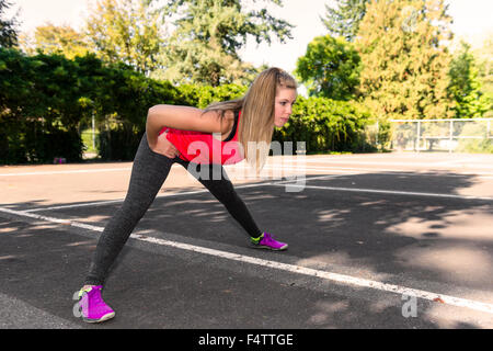 Ein Fit weibliche Läufer stoppt, um in eine urbane Parklandschaft zu dehnen. Stockfoto