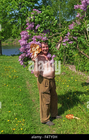Handgefertigte Holz Vase und Löffel geschnitzt. Porträt des Holzschnitzers in der Nähe von lila Baum. Stockfoto