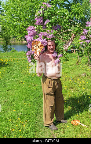 Handgefertigte Holz Vase und Löffel geschnitzt. Porträt des Holzschnitzers in der Nähe von lila Baum. Stockfoto