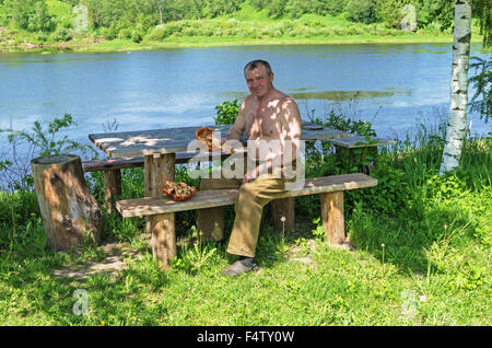 Handgefertigte Holz Vase und Löffel geschnitzt. Porträt des Holzschnitzers an der Fluss-Küste. Stockfoto
