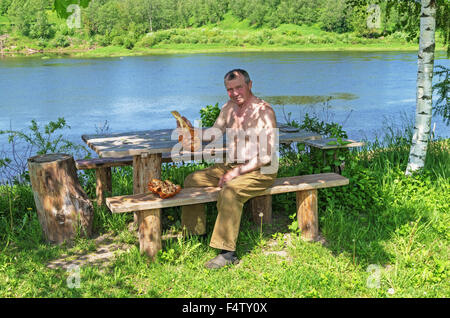 Handgefertigte Holz Vase und Löffel geschnitzt. Porträt des Holzschnitzers an der Fluss-Küste. Stockfoto