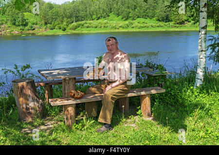 Handgefertigte Holz Vase und Löffel geschnitzt. Porträt des Holzschnitzers an der Fluss-Küste. Stockfoto
