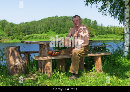 Handgefertigte Holz Vase und Löffel geschnitzt. Porträt des Holzschnitzers an der Fluss-Küste. Stockfoto