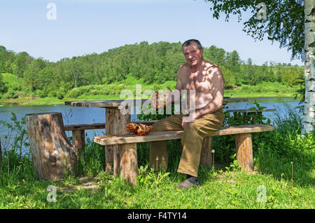 Handgefertigte Holz Vase und Löffel geschnitzt. Porträt des Holzschnitzers an der Fluss-Küste. Stockfoto
