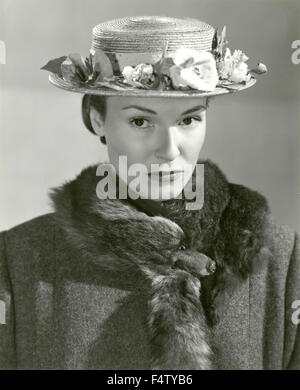 Ein Modell trägt einen Hut mit Blumen und einem Pelzkragen Stockfoto