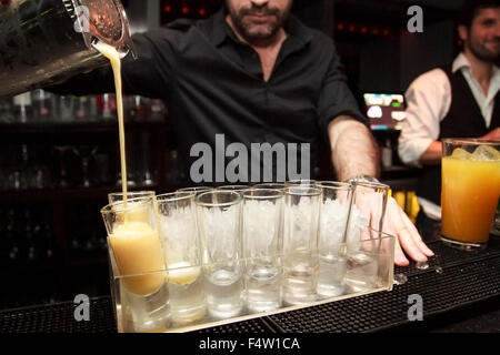 Barkeeper Gießen cocktail Aufnahmen auf einem Tablett voller Schnapsgläser Stockfoto