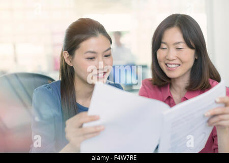 Lächelnde Geschäftsfrauen diskutieren Papierkram im Büro Stockfoto