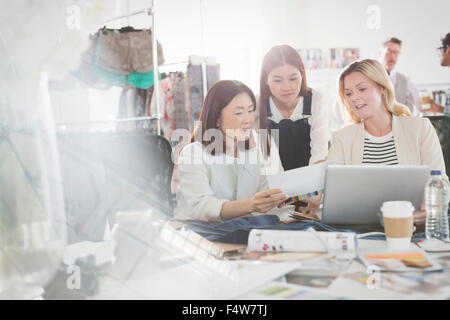 Mode-Designer diskutieren Papierkram am Laptop im Büro Stockfoto