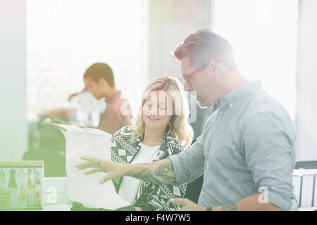 Mode-Designer diskutieren Stoffmuster im sonnigen Büro Stockfoto