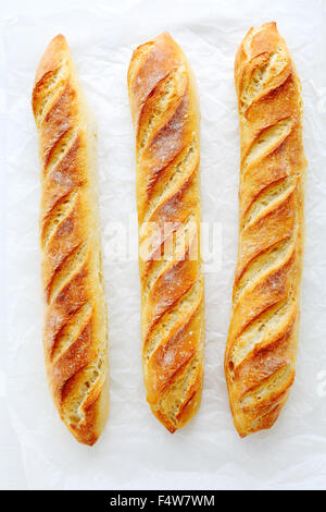 frisches Baguette auf weißem Papier, Ansicht von oben Stockfoto