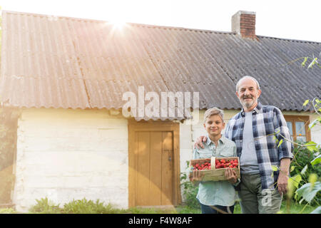 Porträt stolzer Großvater und Enkel mit geernteten Erdbeeren Stockfoto