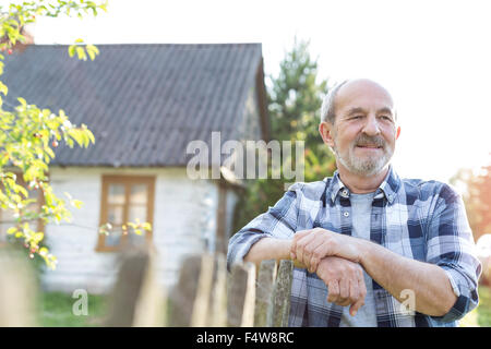 Zuversichtlich Landwirt stützte sich auf Zaun außerhalb Bauernhaus Stockfoto