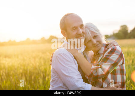 Liebevolle ruhige älteres paar umarmt im sonnigen ländlichen Weizenfeld Stockfoto