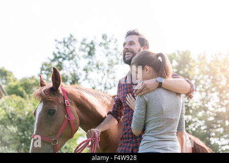 Lächelnde paar umarmt in der Nähe von Pferd Stockfoto