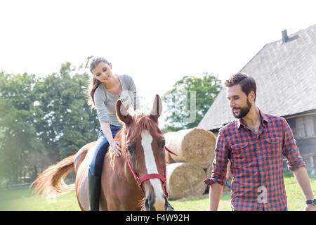 Mann führende Frau Reiten in ländlichen Weide Stockfoto