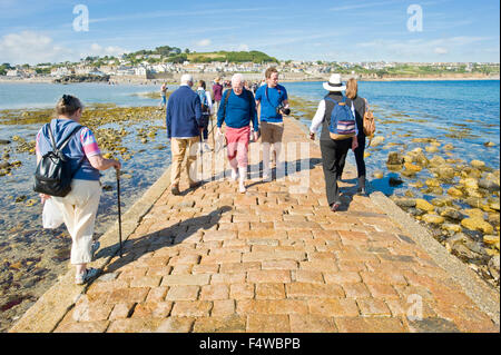 Ein Blick auf die Menschen zu Fuß zum und vom St. Michaels Mount entlang der Damm mit der Stadt von Marazion im Hintergrund. Stockfoto