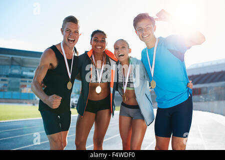 Porträt des jungen Team von Sportlern Sieg zu genießen. Heterogene Gruppe von Läufern mit Medaillen, Erfolge feiern. Stockfoto