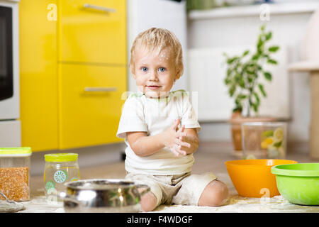Kleiner Junge spielt mit Geschirr und Lebensmittel in der Küche Stockfoto