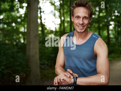 Schöne freundliche muskulöse Sportler seine Stoppuhr einstellen, als er für einen Trainingslauf im Freien im Park in einem Gesundheit bereitet und Stockfoto