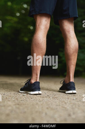 Rückansicht der Beine ein Fit muskulös sportlicher Mann mit durchtrainierten Waden stehen im Freien in seiner Sportbekleidung Stockfoto