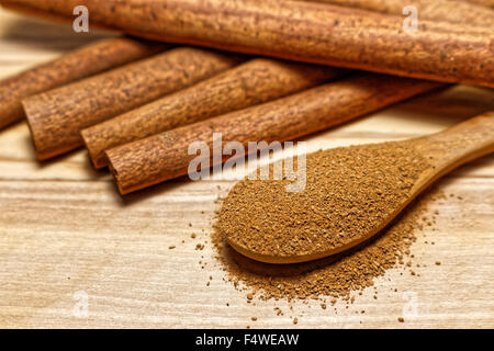 Zimt-sticks mit Zimtpulver in Holzlöffel auf Holzsockel Stockfoto