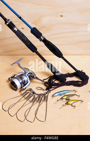 Angelruten und Rollen mit Kunststoff Köder. Fisch-Stringer auf dem hölzernen Hintergrund. Stockfoto