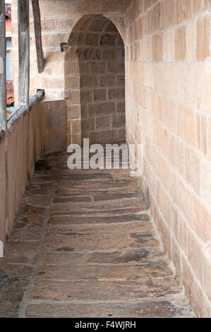 Schmale Passage Kopfsteinpflaster mit Bögen außerhalb der Kirche St. Nikolaus in Orio. Baskisches Land. Stockfoto