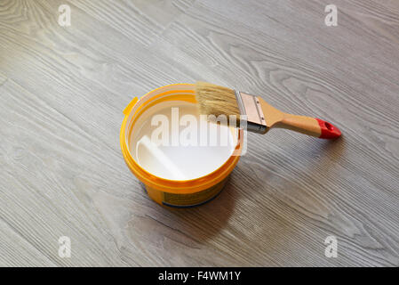 Bank mit weißer Farbe und Pinsel auf Etage Stockfoto