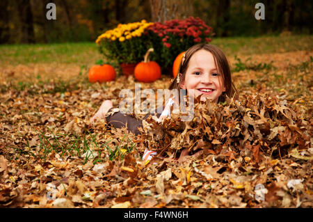 Mädchen spielen im Herbstlaub Stockfoto