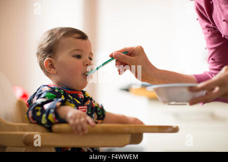 Baby Essen mit Hilfe seiner Mutter Stockfoto