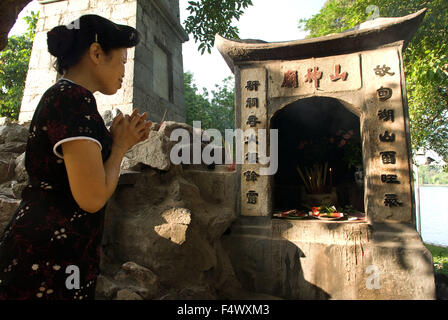 Frau an der The Huc Brücke nach Ngoc Son Tempel (Jade Mountain) in Hoan Kiem beten. Hanoi Old Quarter. Huc Brücke nach Ngoc Son Tempel, Jade Mountain Tempel, Hoan-Kiem-See, Hanoi, Nordvietnam, Vietnam, Südostasien, Asien Stockfoto