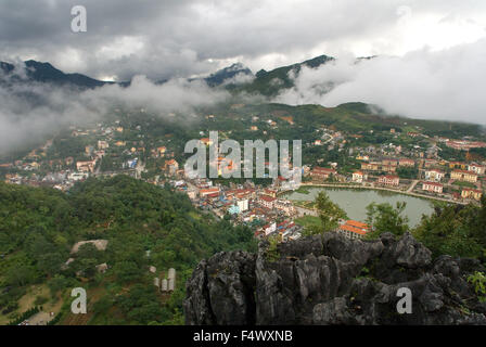 Sapa-Dorf. Luftaufnahme von Clustern von Gebäuden eingebettet im grünen Tal von Sapa, Vietnam. Blick über Sapa Stadt mit Wolken Rollen durch Berge Vietnam. Stockfoto