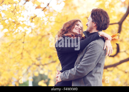 Lächelnde paar umarmt im Herbst Park auf gelben Ahorn Baum Hintergrund Stockfoto