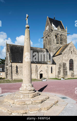 Milliarium Stein platziert neben Römerstraßen und Sainte-Mère-Église Kirche mit Fallschirm Memorial, Normandie, Frankreich Stockfoto