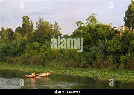 Sauberes nettes Mädchen Kleidung in einem hölzernen Sampan macht seinen Weg auf dem braunen Wasser des Parfüm-Flusses in Hue, Vietnam. Stockfoto