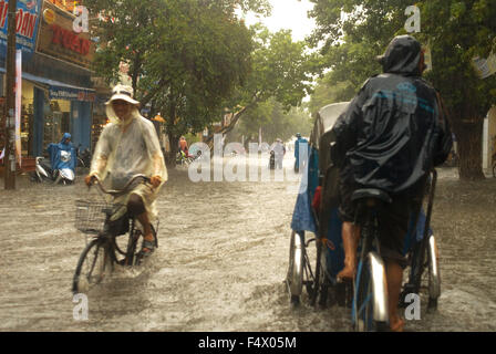 Monsunregen in der Stadt Hue. Menschen in Tuc-Tuc-Fahrten mit dem Fahrrad entlang überfluteten Straßen in Hue. Vietnam. Stockfoto