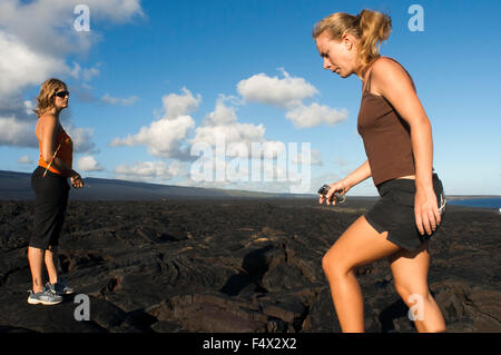 Touristen zu Fuß über die schwarze Lava-Berge in der Nähe der Küste und der Autobahn Chain of Crater Road. Hawaii Volcanoes National Park. Stockfoto