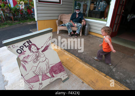 Schild "geöffnet". Mädchen zu Fuß. Typische Häuser und Geschäfte in Hawi. Big Island. Hawi ist die nördlichste Stadt. Häuser aus Holz lackiert Stockfoto