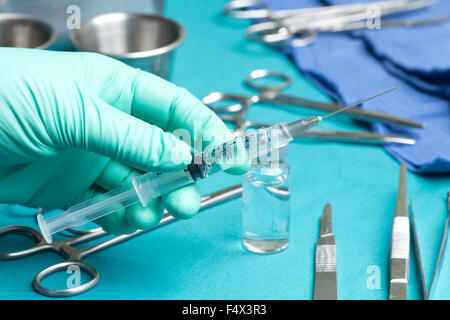 Techniker zeichnet Medikamente mit Spritze während chirurgischer Eingriff. Stockfoto